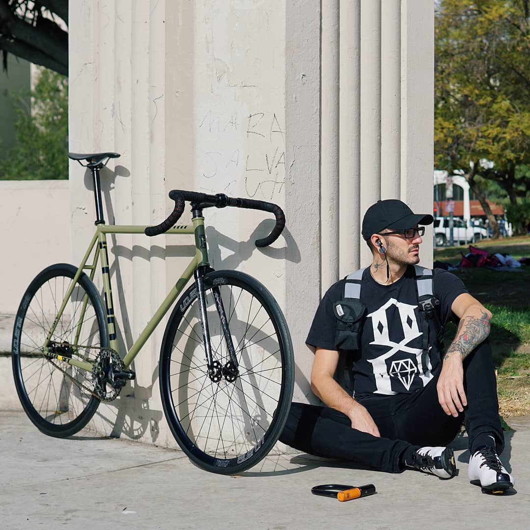 Cyclist taking a rest and leaning up by his bike while staring off to the distance